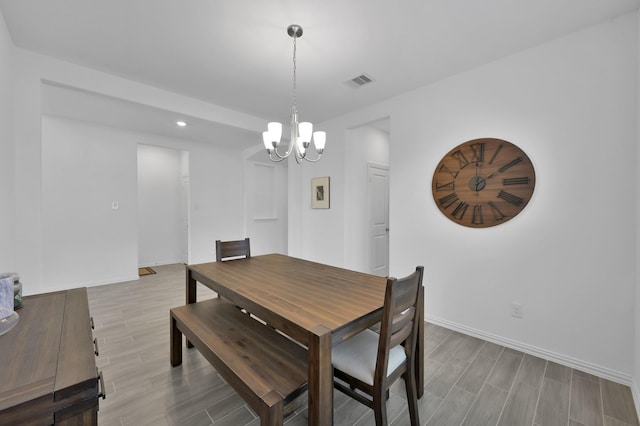 dining space with a notable chandelier, visible vents, baseboards, and wood finish floors