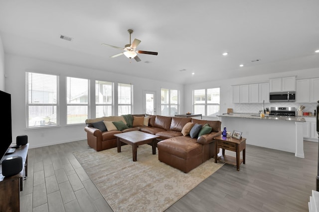 living area featuring visible vents, light wood-style flooring, recessed lighting, baseboards, and ceiling fan