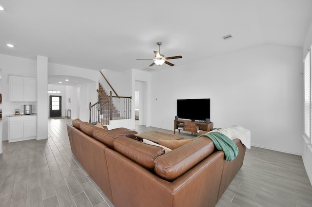 living area featuring visible vents, stairway, arched walkways, ceiling fan, and wood tiled floor