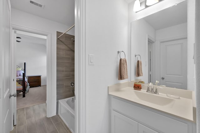 bathroom with visible vents, connected bathroom, wood finish floors, shower / tub combination, and vanity