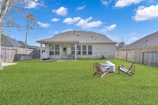 rear view of property with brick siding, a fenced backyard, a patio, and a yard