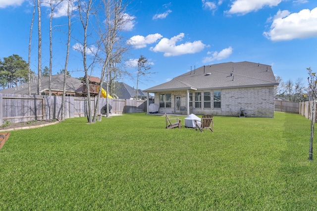 rear view of property with a yard, a fenced backyard, and brick siding