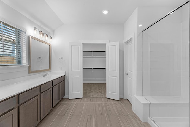 full bath featuring vanity, a spacious closet, recessed lighting, and a tile shower