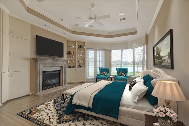 bedroom with visible vents, a raised ceiling, light wood-style floors, and a fireplace