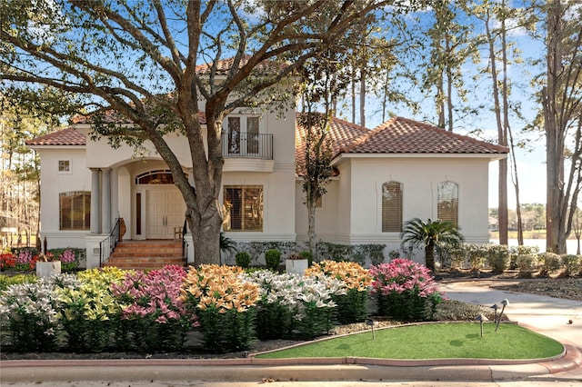 mediterranean / spanish house with a tiled roof, a balcony, and stucco siding