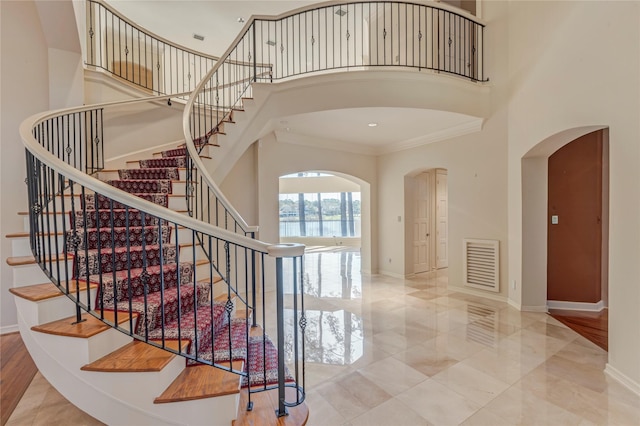 stairway with a high ceiling, visible vents, and baseboards