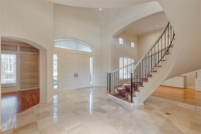 entryway with stairway, a healthy amount of sunlight, baseboards, and a towering ceiling