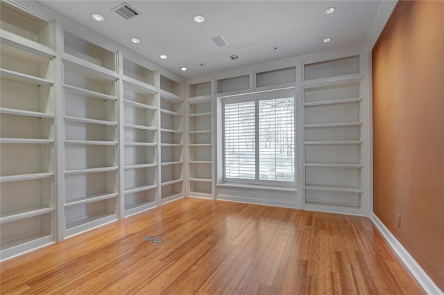 unfurnished room with recessed lighting, visible vents, built in shelves, and wood finished floors