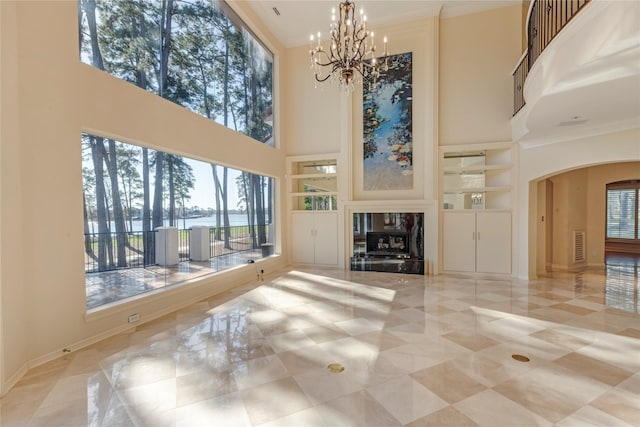 living room with built in features, arched walkways, a water view, and a premium fireplace