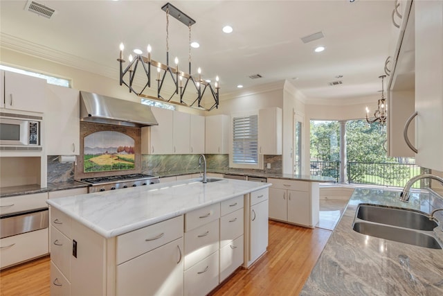 kitchen featuring visible vents, ornamental molding, a sink, appliances with stainless steel finishes, and exhaust hood