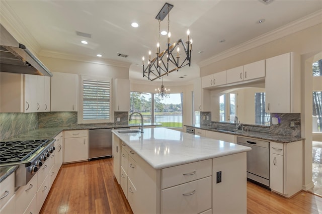 kitchen with visible vents, light wood-style flooring, ornamental molding, a sink, and appliances with stainless steel finishes