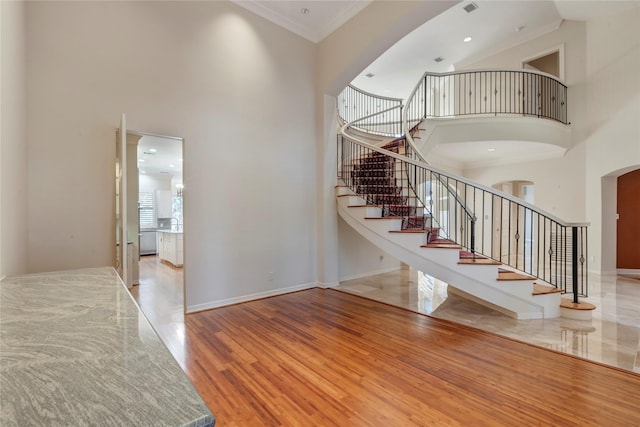 foyer featuring baseboards, a high ceiling, wood finished floors, and ornamental molding