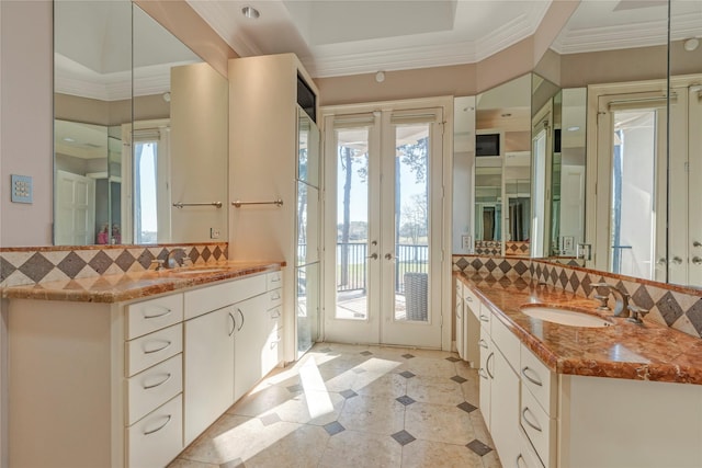 full bath featuring two vanities, ornamental molding, backsplash, and a sink