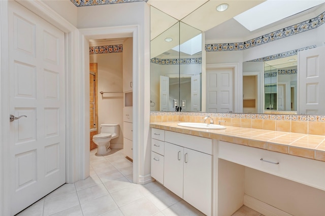 bathroom with toilet, decorative backsplash, a skylight, tile patterned floors, and vanity