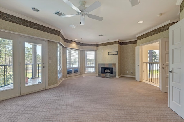 unfurnished living room with visible vents, wallpapered walls, ornamental molding, carpet flooring, and a tile fireplace