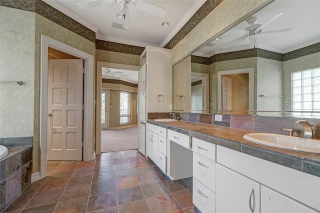 full bath with a sink, stone tile floors, crown molding, and wallpapered walls