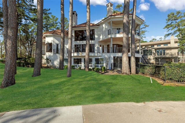 exterior space with a lawn, a balcony, a chimney, and a tile roof