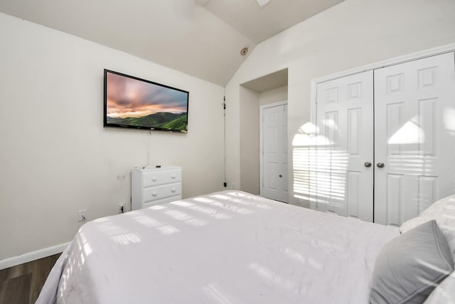 bedroom with vaulted ceiling, baseboards, dark wood-style flooring, and a closet