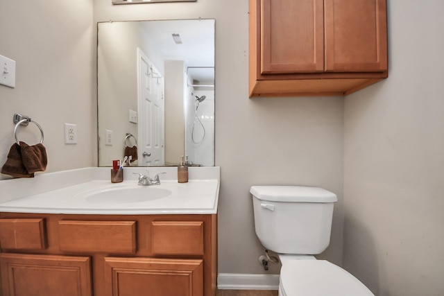 bathroom with vanity, toilet, baseboards, and walk in shower