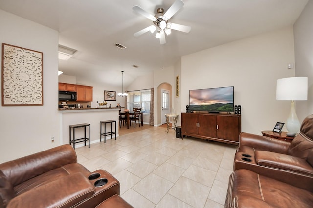 living room featuring light tile patterned floors, visible vents, lofted ceiling, and a ceiling fan