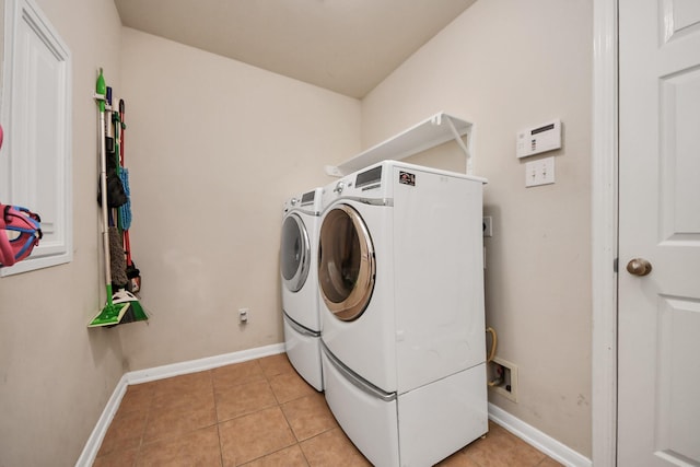 washroom with laundry area, light tile patterned floors, baseboards, and washer and clothes dryer