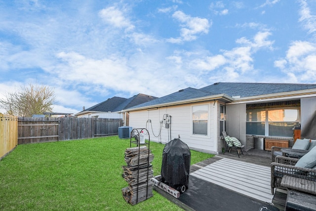 rear view of house featuring central air condition unit, a lawn, and a fenced backyard