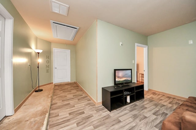 hallway with visible vents, attic access, baseboards, and wood finished floors