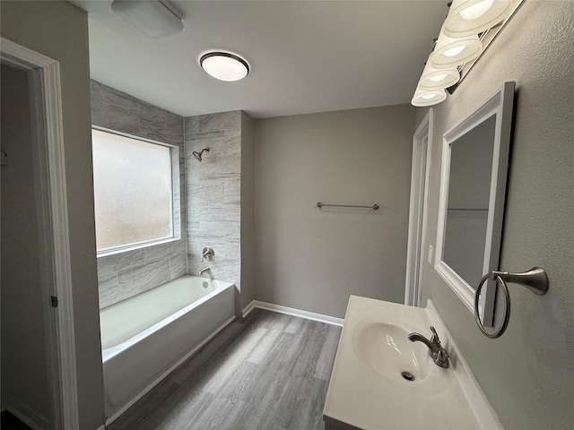 bathroom featuring vanity, wood finished floors, baseboards, and shower / bathtub combination