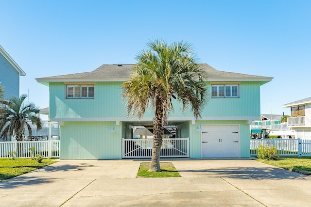 beach home featuring fence, a garage, and driveway