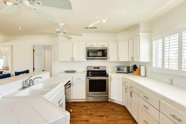 kitchen with dark wood-style floors, visible vents, a sink, appliances with stainless steel finishes, and tasteful backsplash