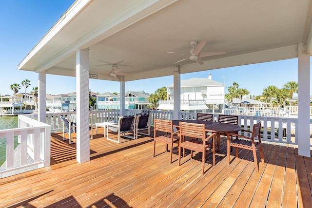 wooden deck featuring a residential view, outdoor dining area, ceiling fan, and a water view