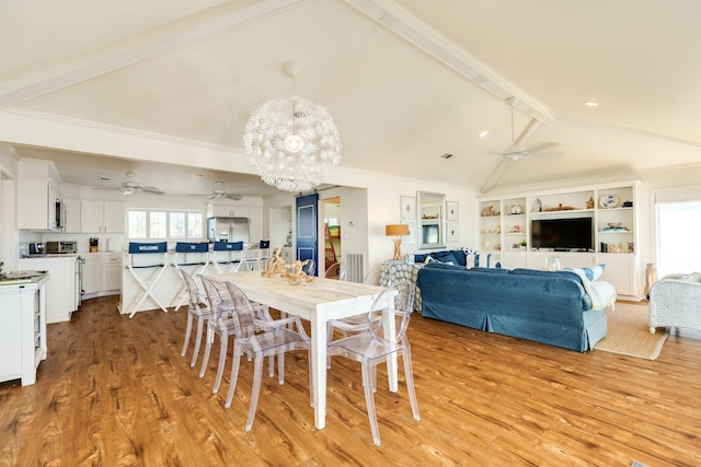 dining space with beam ceiling, light wood-style flooring, ceiling fan with notable chandelier, and ornamental molding