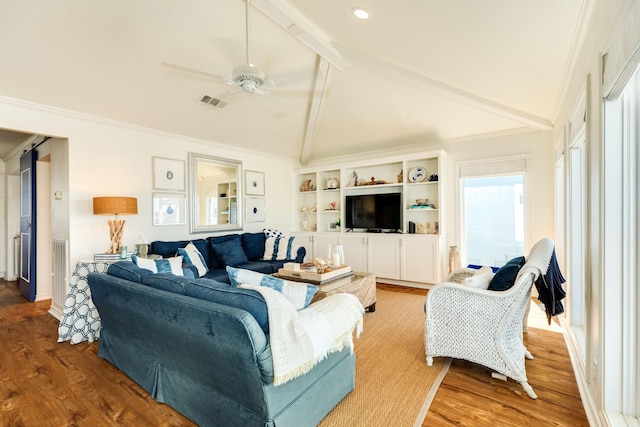 living area with visible vents, crown molding, beamed ceiling, wood finished floors, and a ceiling fan