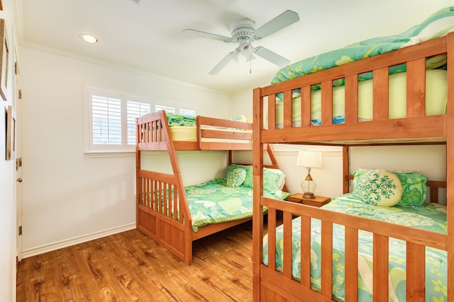 bedroom featuring a ceiling fan, crown molding, baseboards, and wood finished floors