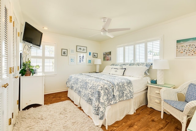 bedroom with ceiling fan, baseboards, wood finished floors, and ornamental molding