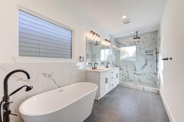 bathroom with a marble finish shower, visible vents, a freestanding bath, double vanity, and a sink