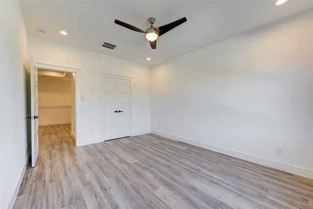 unfurnished bedroom featuring baseboards, visible vents, attic access, light wood-style flooring, and recessed lighting