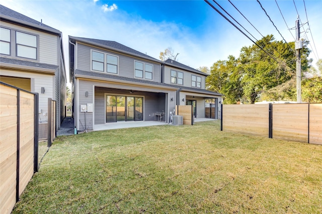 rear view of house with ceiling fan, central AC unit, a lawn, a fenced backyard, and a patio area