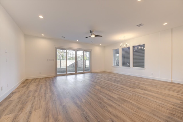 spare room with visible vents, baseboards, recessed lighting, light wood-style flooring, and ceiling fan with notable chandelier