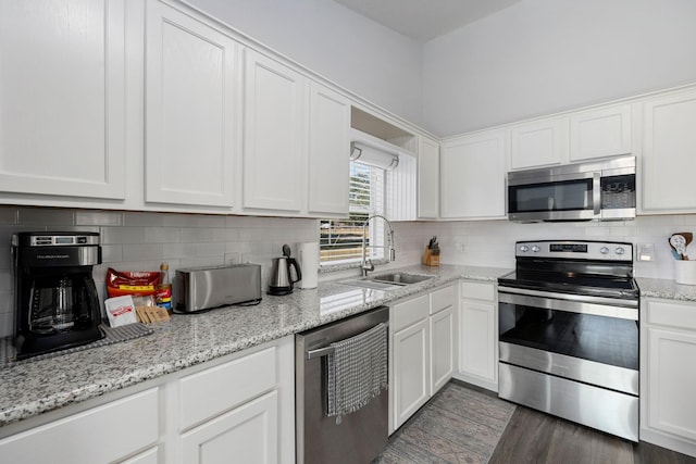 kitchen featuring a sink, light stone counters, appliances with stainless steel finishes, white cabinets, and decorative backsplash