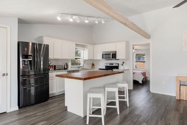 kitchen with a breakfast bar area, lofted ceiling with beams, decorative backsplash, stainless steel appliances, and wood counters