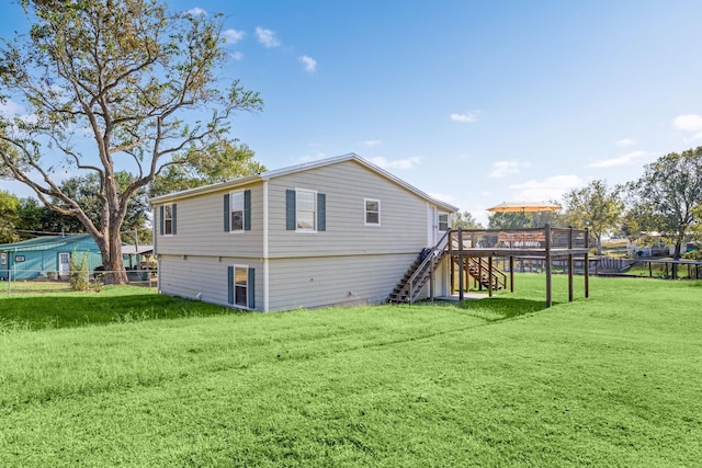 rear view of property with stairs, a deck, a lawn, and fence