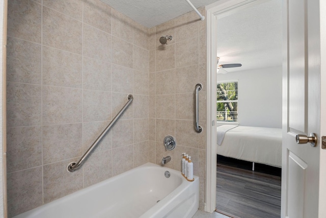 ensuite bathroom with a ceiling fan, a textured ceiling, wood finished floors, connected bathroom, and washtub / shower combination