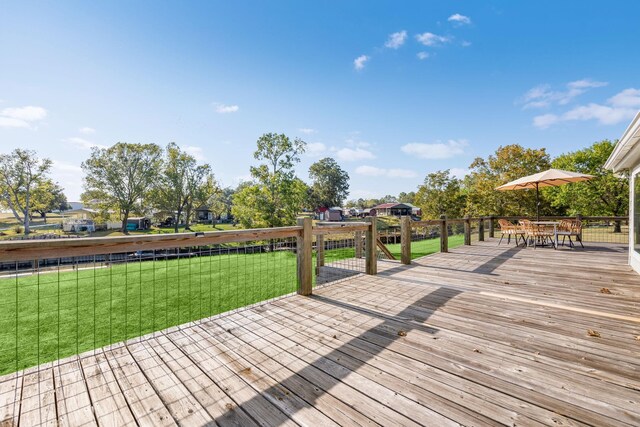 wooden deck with outdoor dining space and a lawn