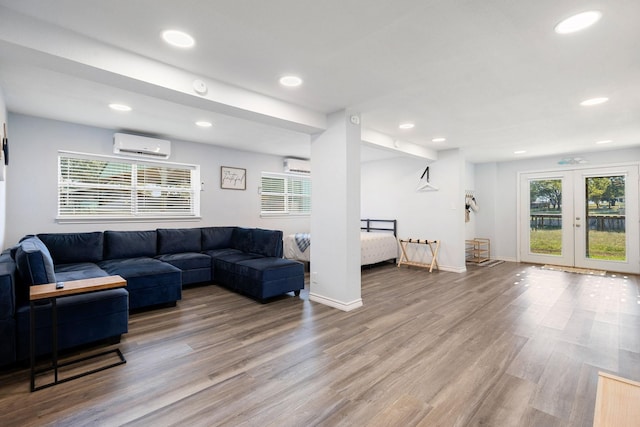 living area featuring a wall unit AC, wood finished floors, and a healthy amount of sunlight