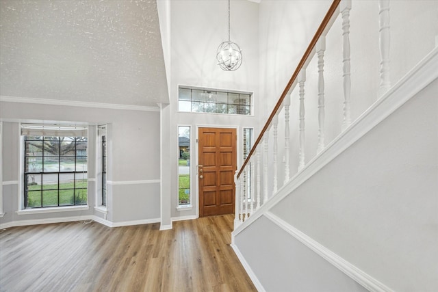 entrance foyer with a textured ceiling, wood finished floors, stairway, baseboards, and a chandelier