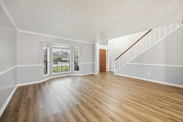 unfurnished living room featuring stairway, a textured ceiling, baseboards, and wood finished floors