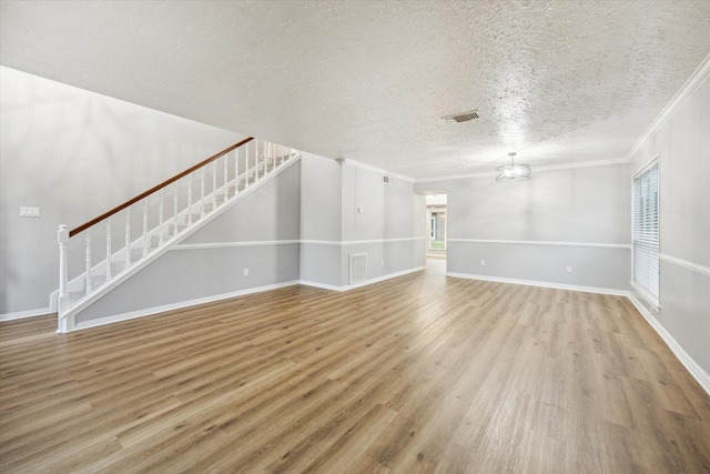 unfurnished living room featuring visible vents, wood finished floors, ornamental molding, and stairway