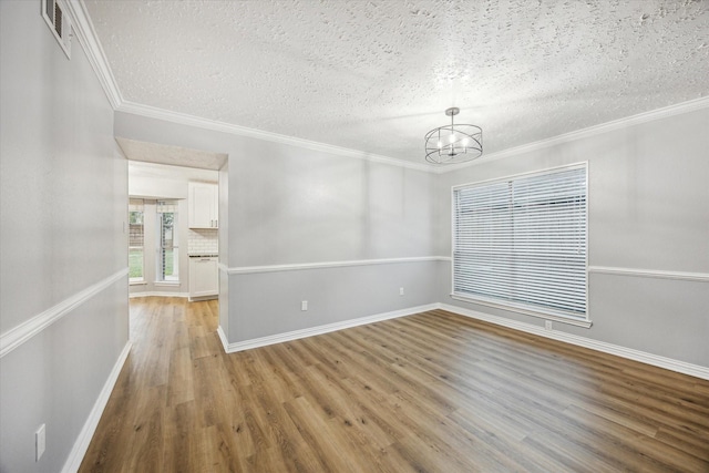 unfurnished room featuring an inviting chandelier, crown molding, light wood finished floors, and a textured ceiling