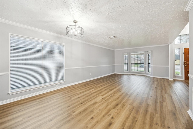 unfurnished living room with wood finished floors, baseboards, a textured ceiling, crown molding, and a notable chandelier